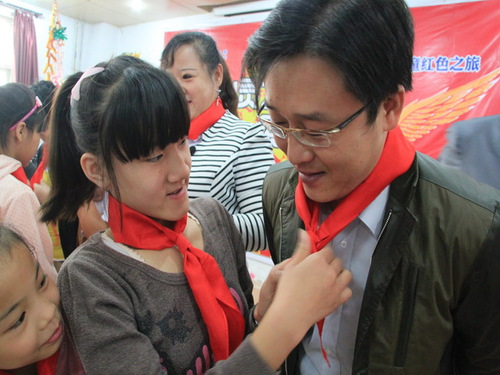 福利院孩子們?yōu)槲宜敬肀R曉巍經(jīng)理佩戴紅領巾